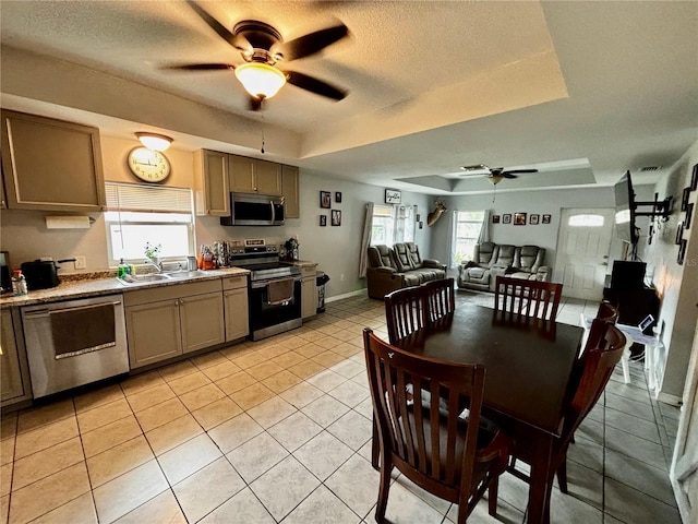 kitchen featuring light tile patterned flooring, stainless steel appliances, a raised ceiling, and sink