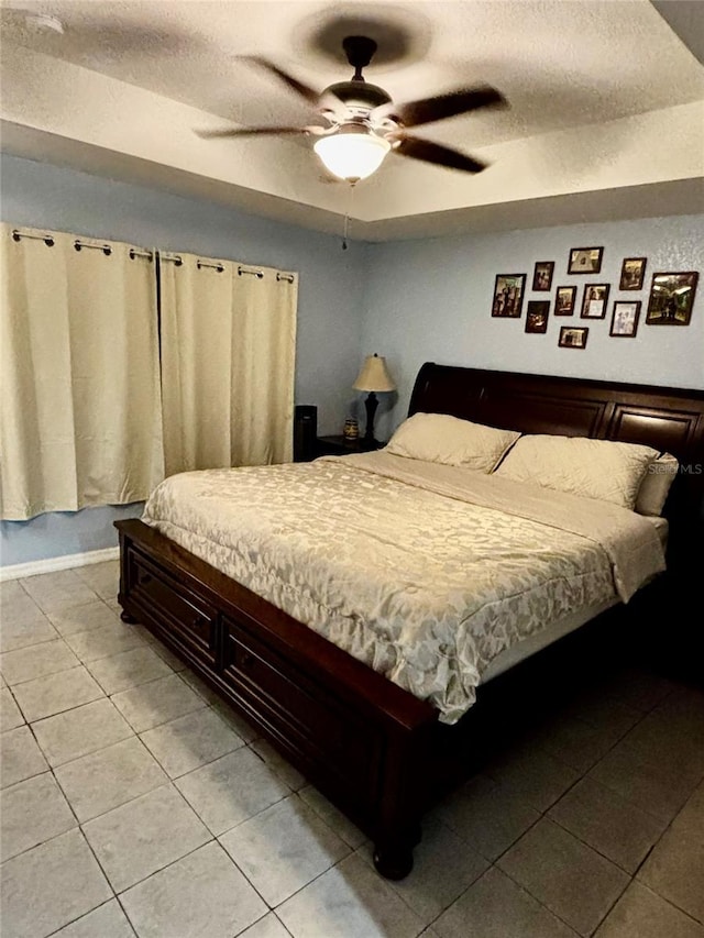 bedroom with ceiling fan, light tile patterned flooring, and a textured ceiling