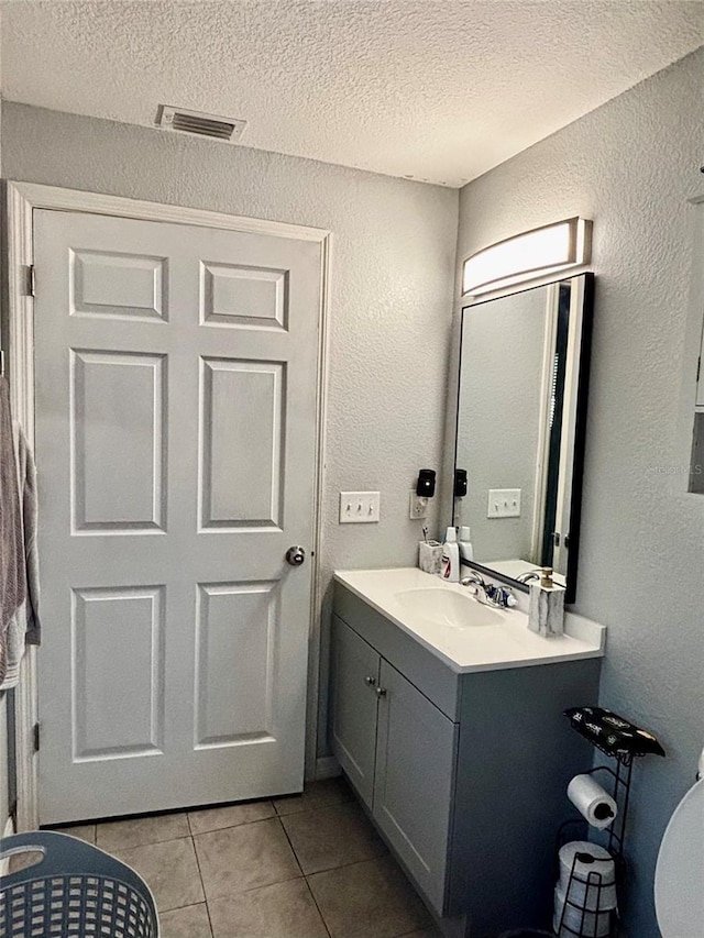 bathroom with tile patterned flooring, vanity, a textured ceiling, and toilet