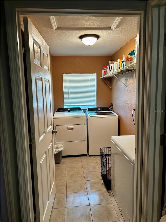 laundry area with crown molding, washing machine and dryer, light tile patterned floors, and a textured ceiling