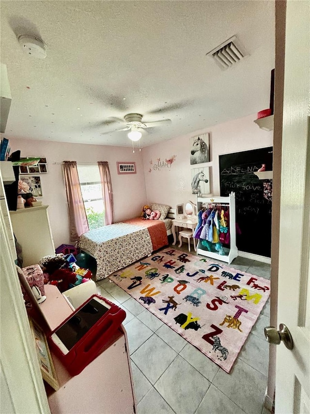 bedroom with ceiling fan, light tile patterned floors, and a textured ceiling