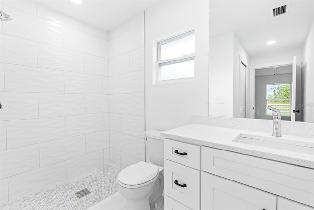 bathroom featuring tiled shower, vanity, and toilet