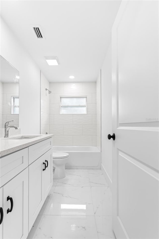 full bathroom with vanity, a healthy amount of sunlight, tiled shower / bath combo, and toilet