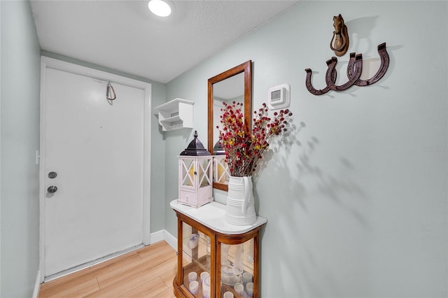 doorway to outside with light wood-type flooring and a textured ceiling