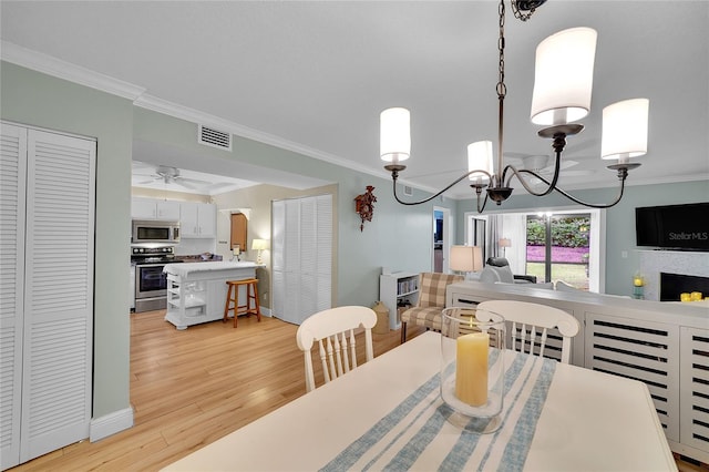 dining area with crown molding, ceiling fan with notable chandelier, and light hardwood / wood-style flooring