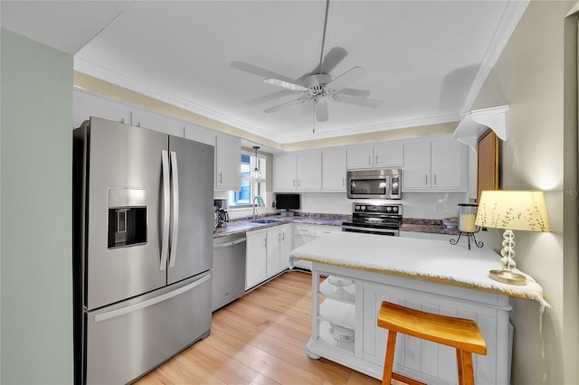 kitchen featuring a kitchen breakfast bar, pendant lighting, appliances with stainless steel finishes, sink, and white cabinets