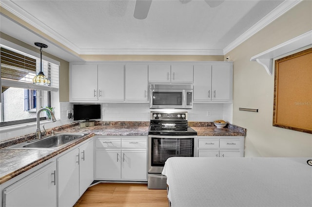 kitchen with pendant lighting, sink, white cabinetry, and appliances with stainless steel finishes