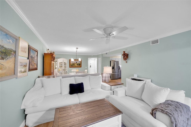 living room featuring ceiling fan with notable chandelier, hardwood / wood-style floors, and crown molding