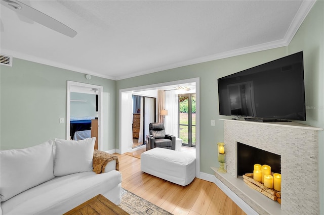 living room with hardwood / wood-style flooring, ornamental molding, ceiling fan, and a fireplace