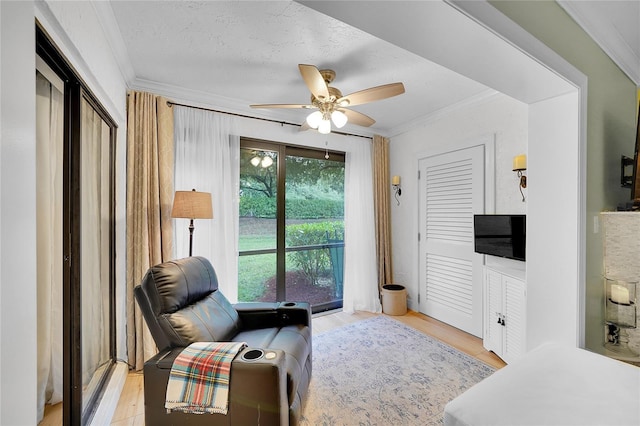 living area featuring ceiling fan, a textured ceiling, ornamental molding, and light wood-type flooring