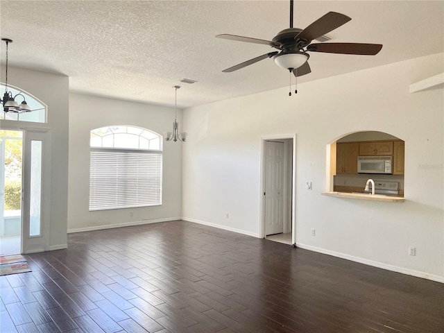 unfurnished living room with sink, a healthy amount of sunlight, ceiling fan with notable chandelier, and a textured ceiling