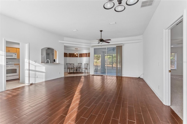 unfurnished living room with wood-type flooring and ceiling fan with notable chandelier