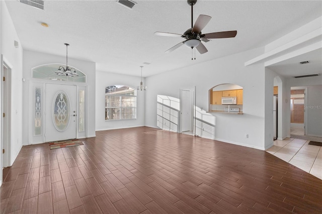 unfurnished living room with hardwood / wood-style flooring, ceiling fan with notable chandelier, and a textured ceiling