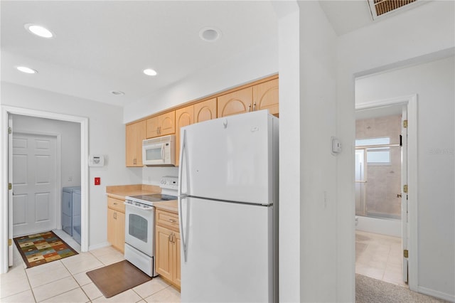 kitchen featuring light tile patterned floors, white appliances, washer and dryer, and light brown cabinets