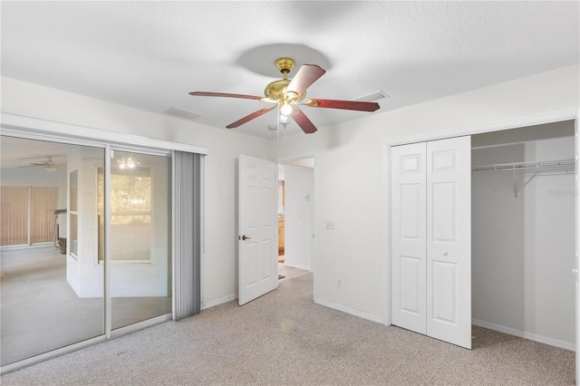 unfurnished bedroom featuring a textured ceiling, light colored carpet, a closet, and ceiling fan