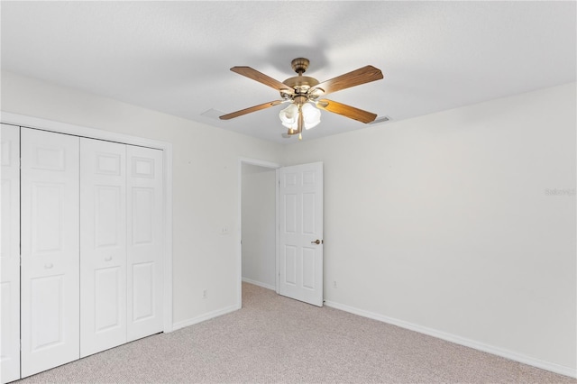 unfurnished bedroom featuring light colored carpet, a closet, and ceiling fan