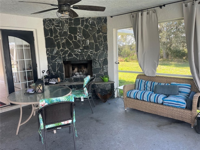 sunroom featuring a fireplace and ceiling fan