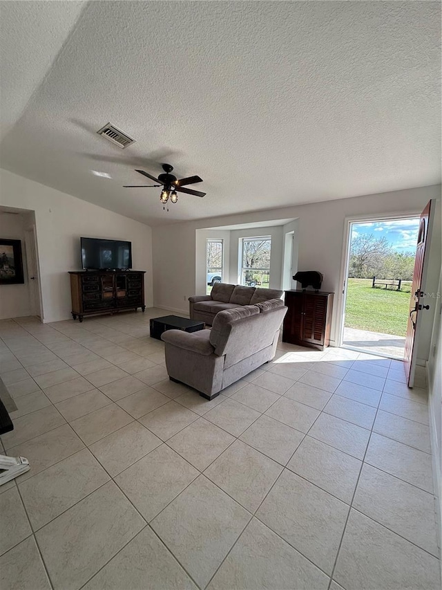 unfurnished living room with lofted ceiling, light tile patterned floors, a wealth of natural light, and ceiling fan