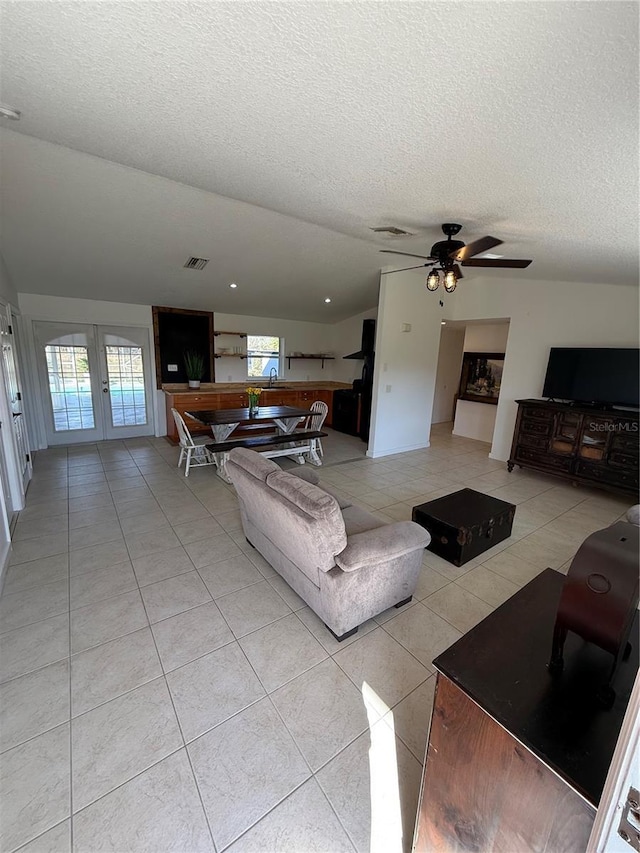 tiled living room featuring french doors, ceiling fan, and a textured ceiling