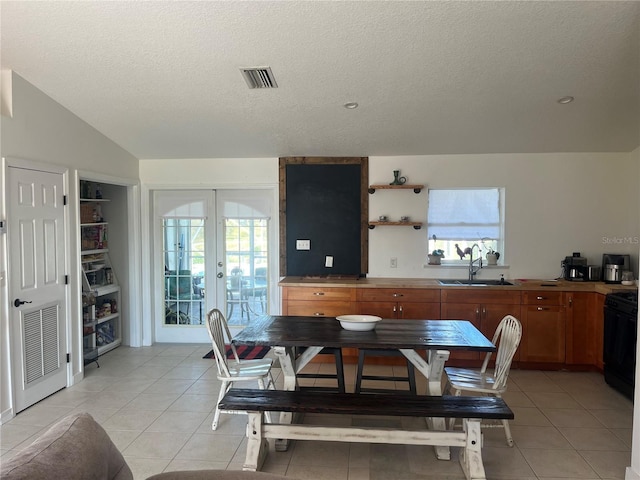 tiled dining room featuring lofted ceiling, sink, a textured ceiling, and french doors