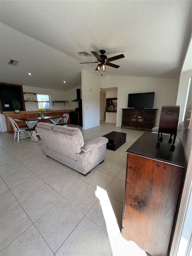 living room featuring light tile patterned floors, a textured ceiling, sink, and ceiling fan