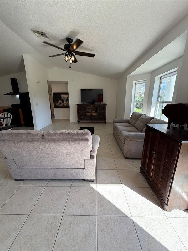 tiled living room featuring vaulted ceiling, ceiling fan, and a textured ceiling