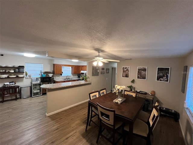 dining space with sink, wine cooler, ceiling fan, a textured ceiling, and light hardwood / wood-style flooring