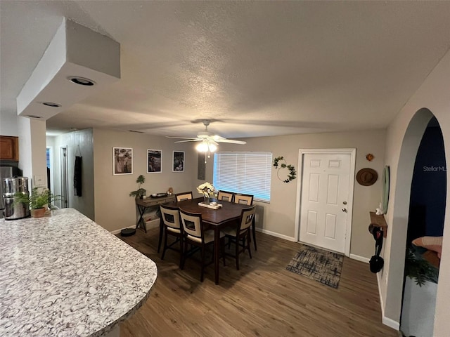 dining area with ceiling fan, dark hardwood / wood-style flooring, and a textured ceiling