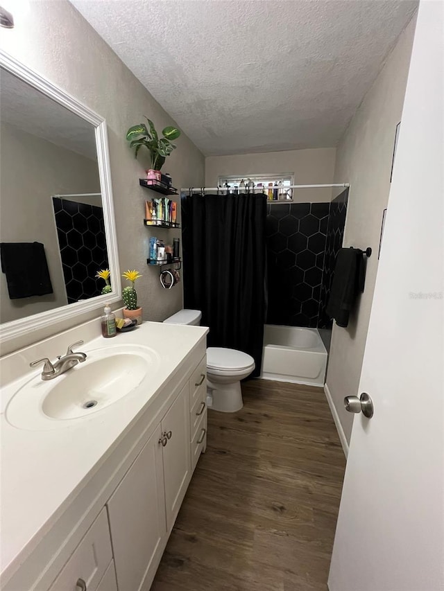 full bathroom featuring shower / tub combo with curtain, wood-type flooring, vanity, toilet, and a textured ceiling