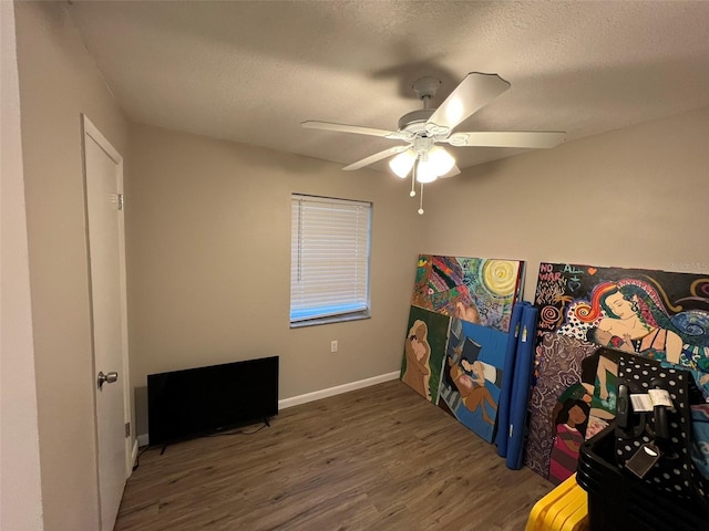 interior space featuring dark wood-type flooring, ceiling fan, and a textured ceiling