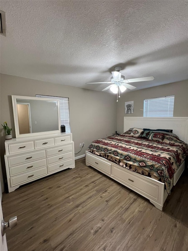 bedroom with dark hardwood / wood-style flooring, a textured ceiling, and ceiling fan