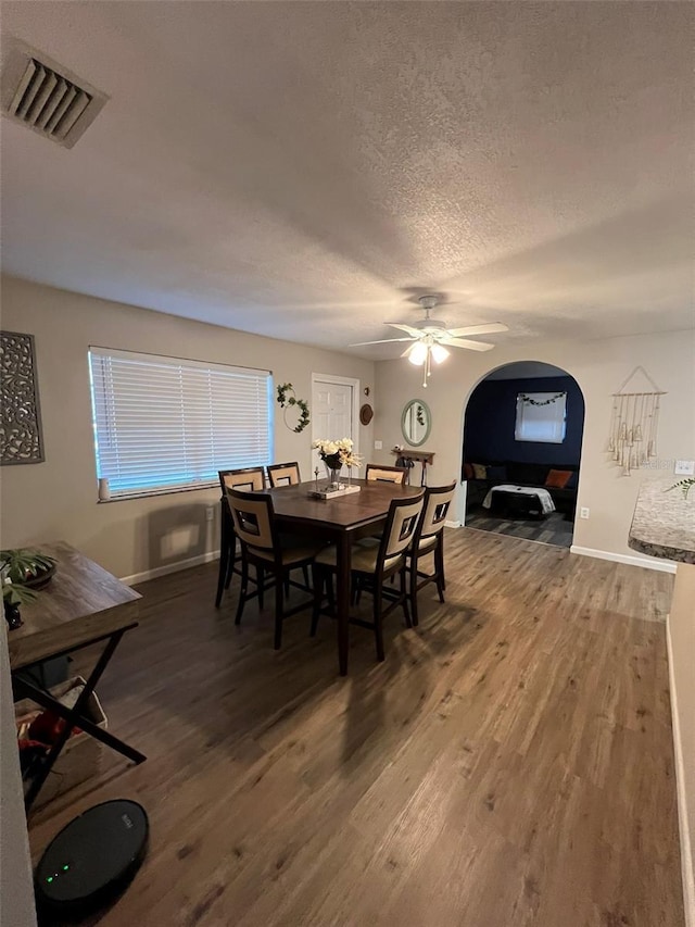 dining area with ceiling fan, hardwood / wood-style flooring, and a textured ceiling