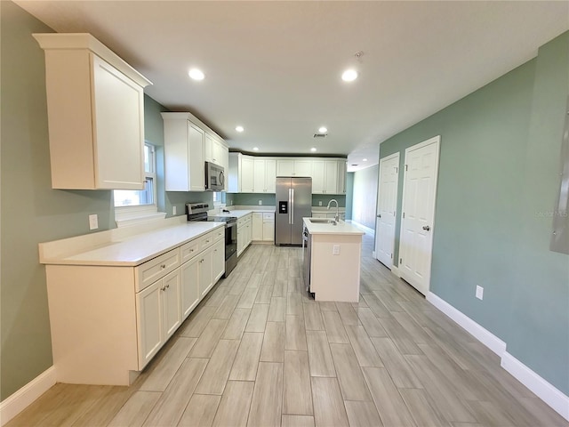 kitchen featuring white cabinetry, stainless steel appliances, sink, and a kitchen island with sink