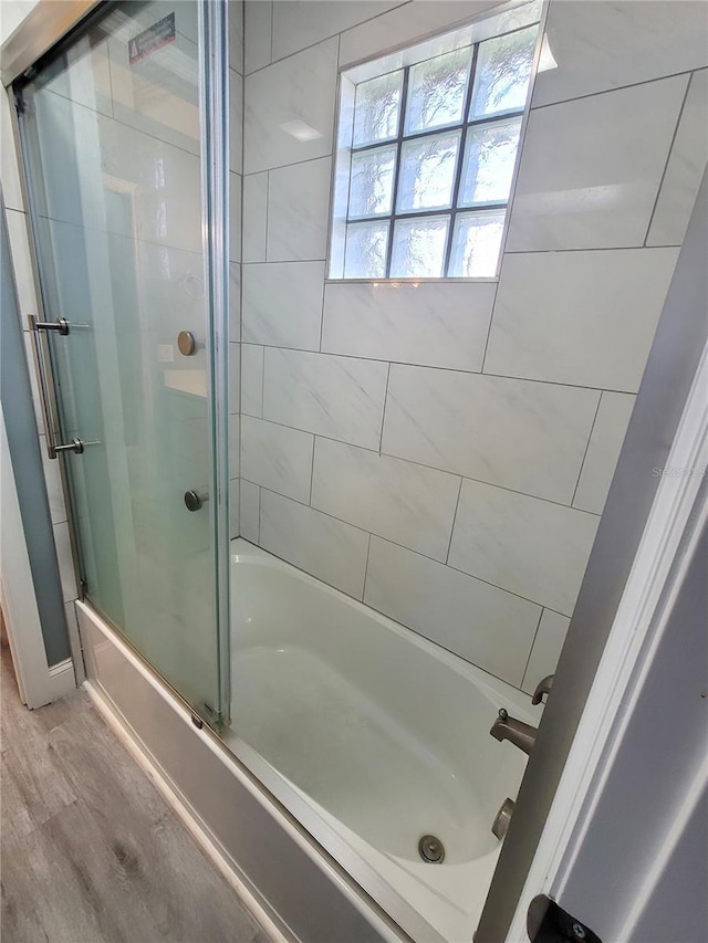 bathroom with hardwood / wood-style flooring and enclosed tub / shower combo