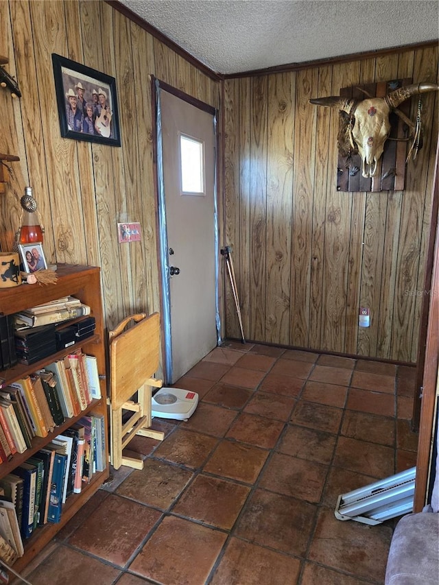 foyer with ornamental molding, a textured ceiling, and wood walls