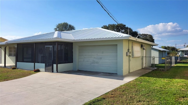 view of front of home featuring a garage, a sunroom, and a front lawn