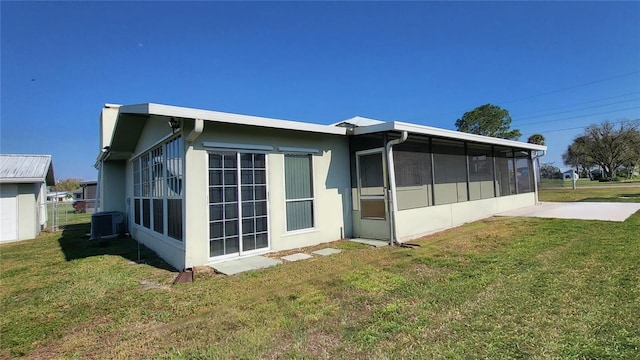 view of property exterior featuring central AC, a yard, and a sunroom