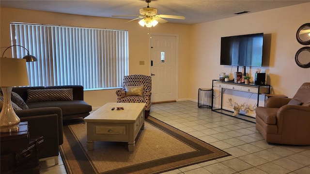 living room featuring light tile patterned flooring, a textured ceiling, and ceiling fan