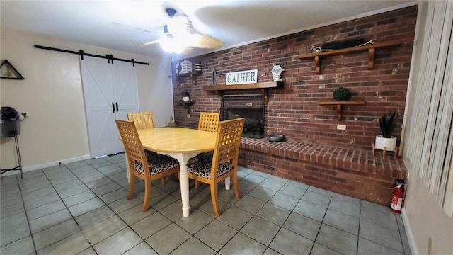 dining room featuring brick wall, light tile patterned flooring, a barn door, and a brick fireplace