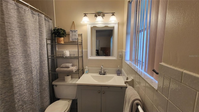 bathroom featuring tile walls, vanity, and toilet