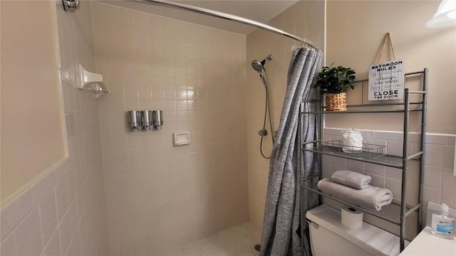 bathroom with tile walls, curtained shower, and toilet