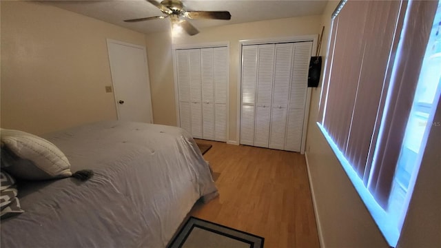 bedroom featuring ceiling fan, multiple closets, and light wood-type flooring