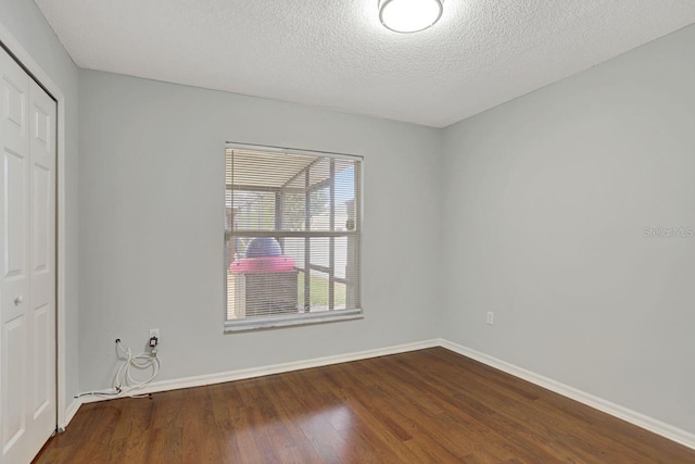 unfurnished bedroom featuring a textured ceiling, a closet, wood finished floors, and baseboards