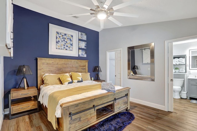 bedroom with connected bathroom, wood finished floors, a ceiling fan, baseboards, and vaulted ceiling