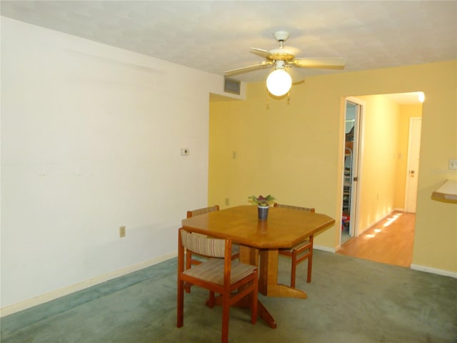 carpeted dining area with ceiling fan