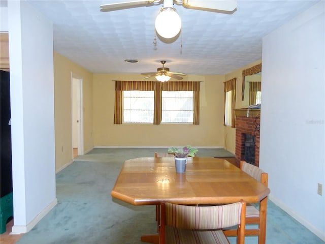 dining space featuring ceiling fan, light colored carpet, and a fireplace