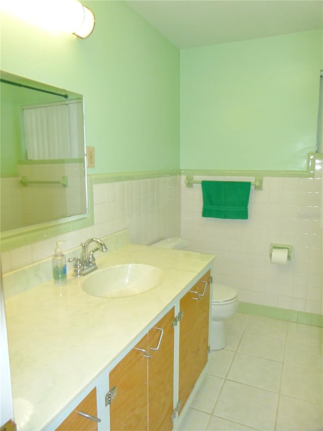 bathroom with tile patterned floors, toilet, vanity, and tile walls