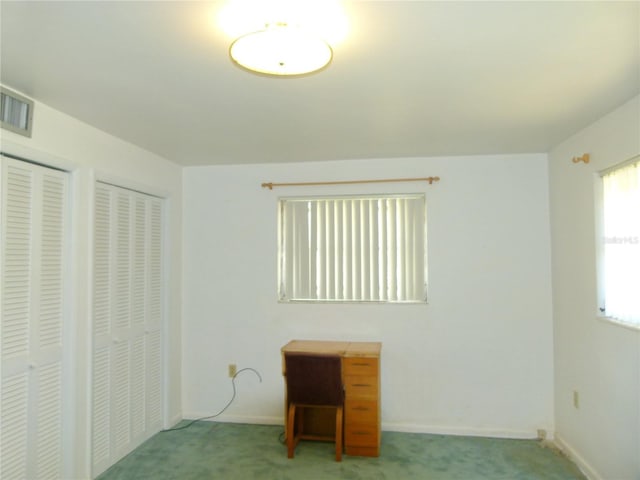 unfurnished bedroom featuring multiple closets and light colored carpet