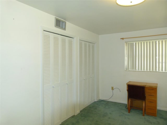 unfurnished bedroom with carpet flooring and two closets