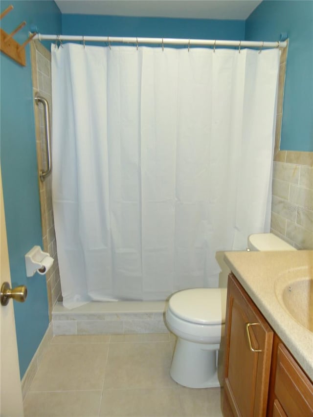 bathroom with vanity, tile patterned flooring, toilet, and walk in shower